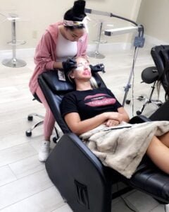 Student carefully applying classic lash extensions to a live model during a training session at Eyeconic Lashes.