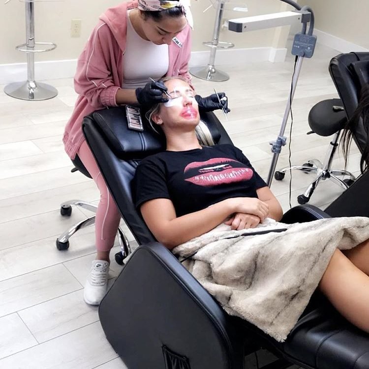 Student carefully applying classic lash extensions to a live model during a training session at Eyeconic Lashes.