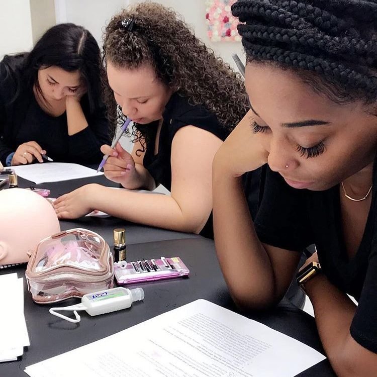 Students attentively taking notes during a lash extension theory class at Eyeconic Lashes.