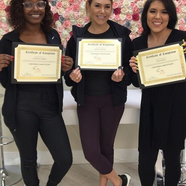 Group of students proudly holding their lash training certificates at Eyeconic Lash Studio.